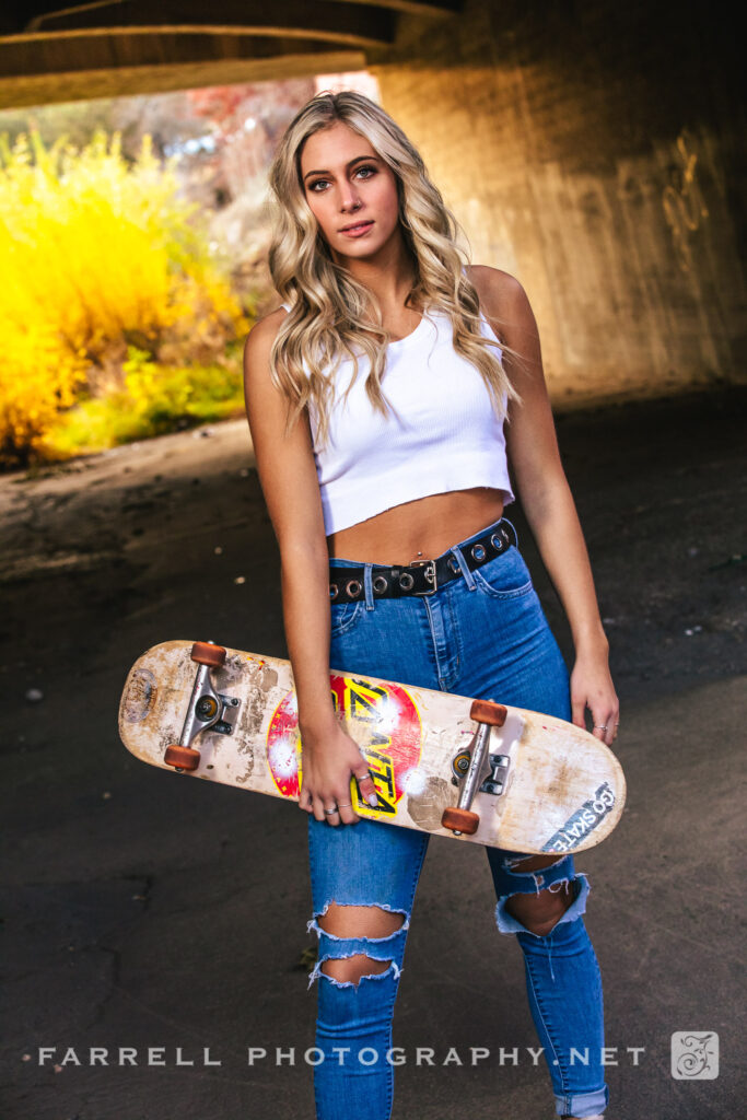 Moody photo of Senior Girl with Skateboard under overpass. High School Girl Senior Portrait